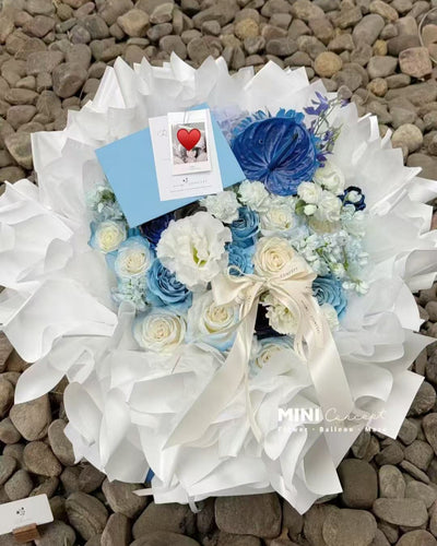 Floral arrangement with blue and white flowers on a pebbled surface